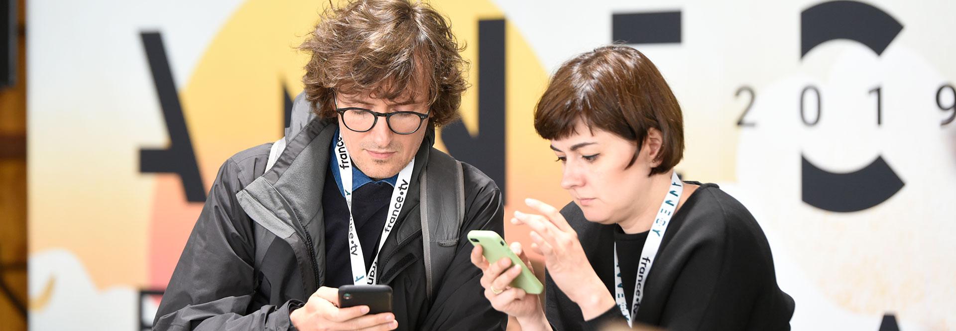 Deux personnes utilisant l'appli mobile du festival. 